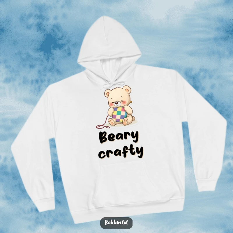 Funny hoodie with a tiny bear happily stitching a colorful quilt square, offering cozy warmth and a touch of crafty charm.