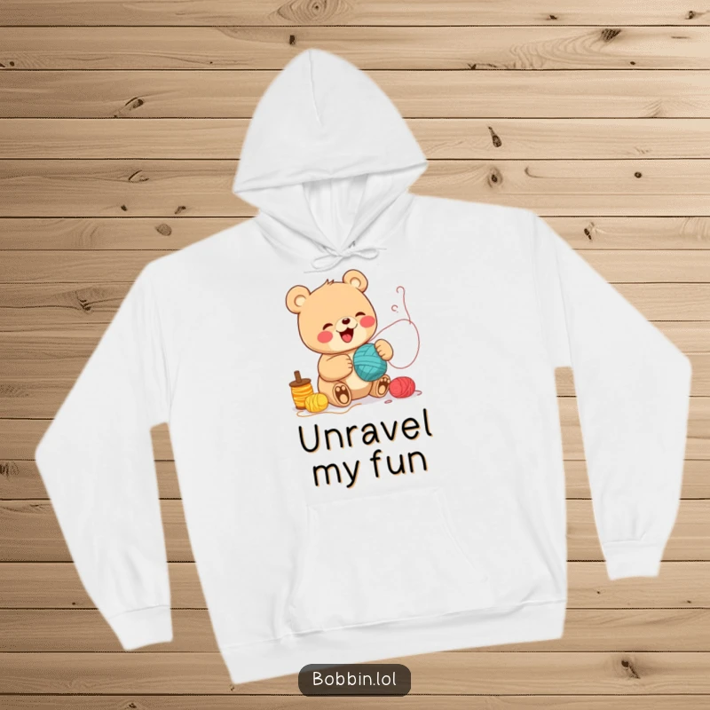 Funny Bear Sewing Hoodie: A cheerful bear giggling while unspooling colorful thread rolls, great for cozy crafting. Perfect funny gift.